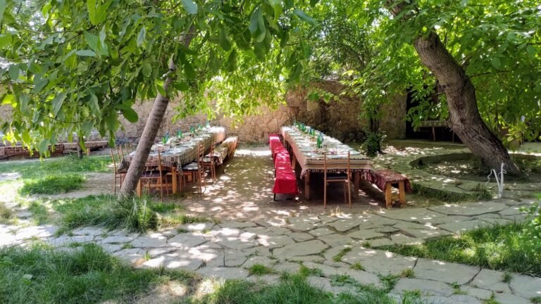 Long dining tables set out in a shaded stone courtyard garden.
